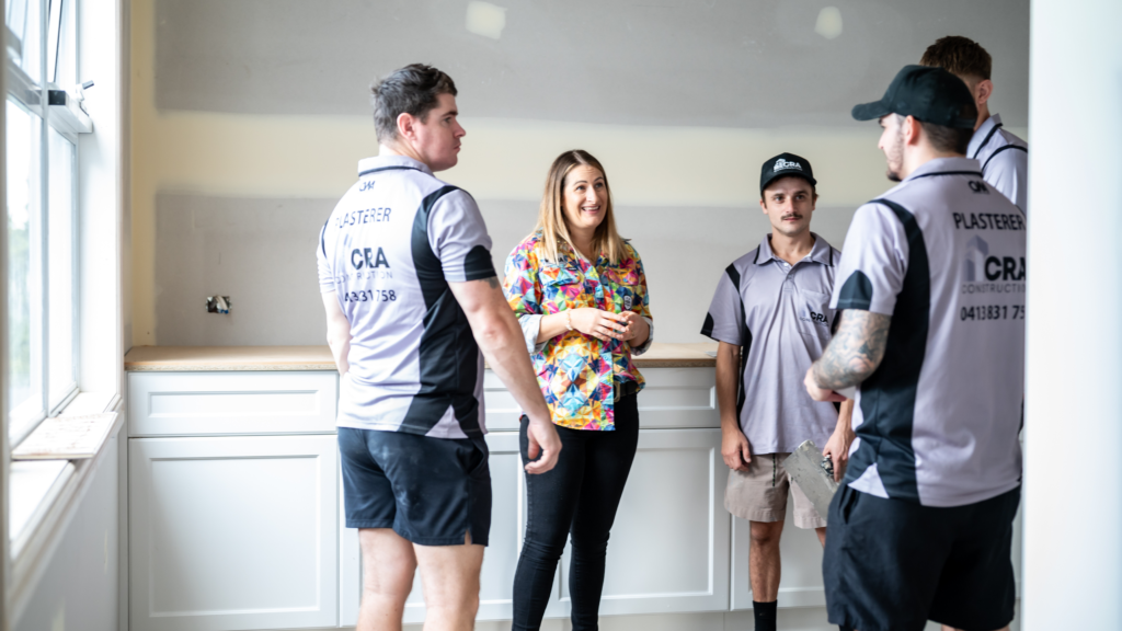 4 members of the CRA team and Co-owner Kim Allan standing in a house with finished plaster behind them. 