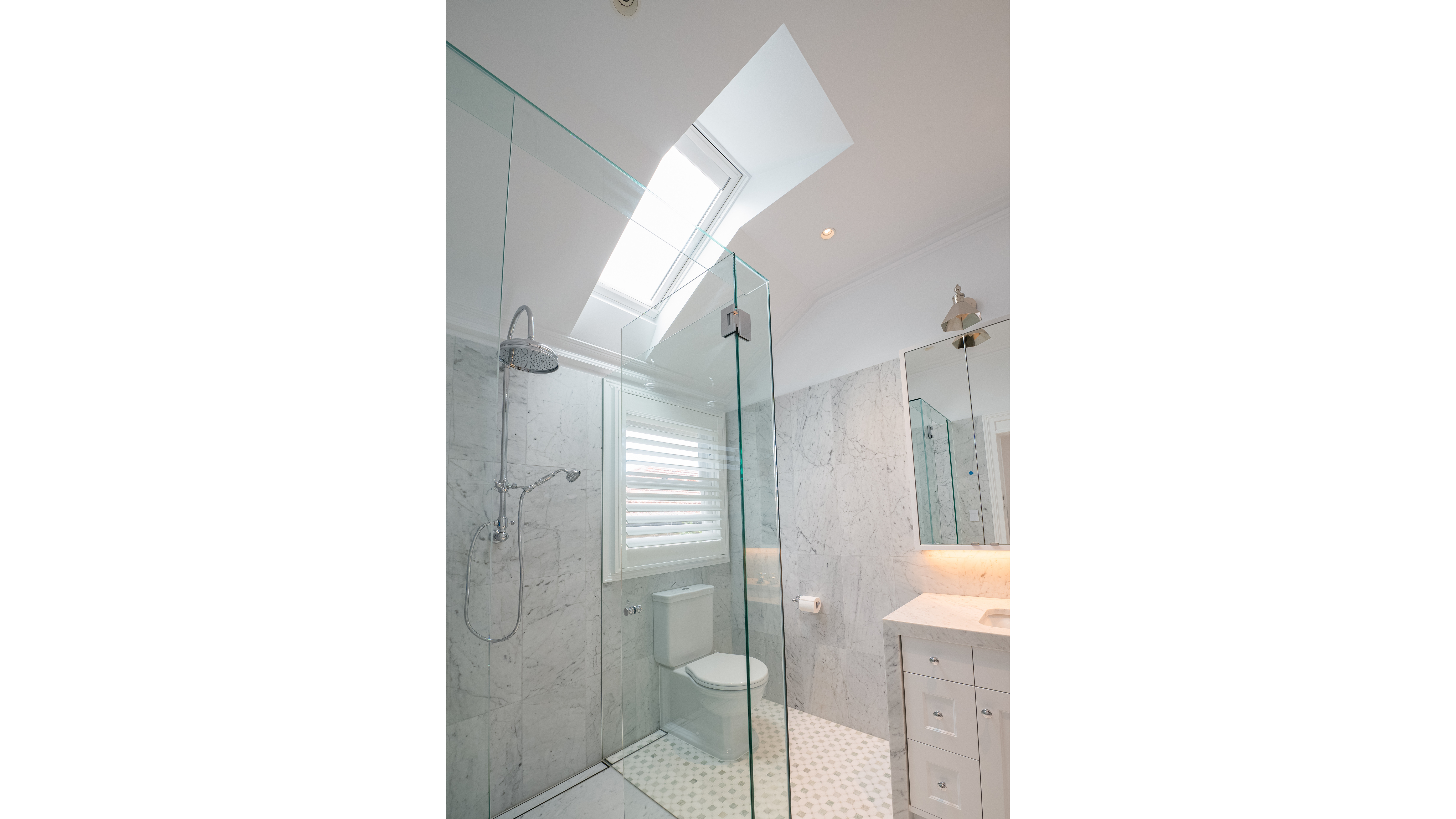 White marble bathroom with a large skylight letting in natural light.