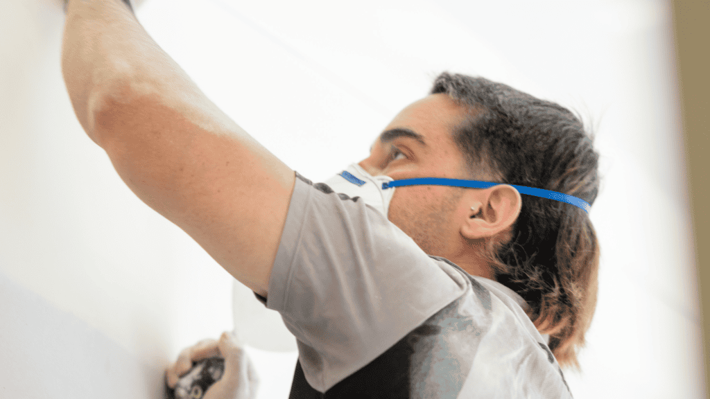 A plasterer wears a filtered mask while working to protect from toxic silica dust.