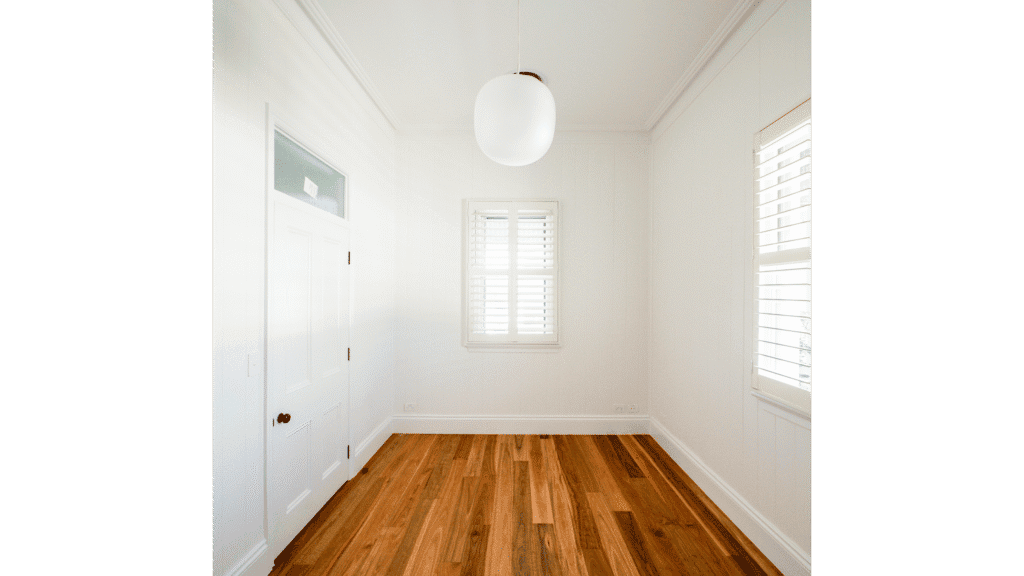 Interior room with white walls, wooden floor, and large windows for natural lighting.