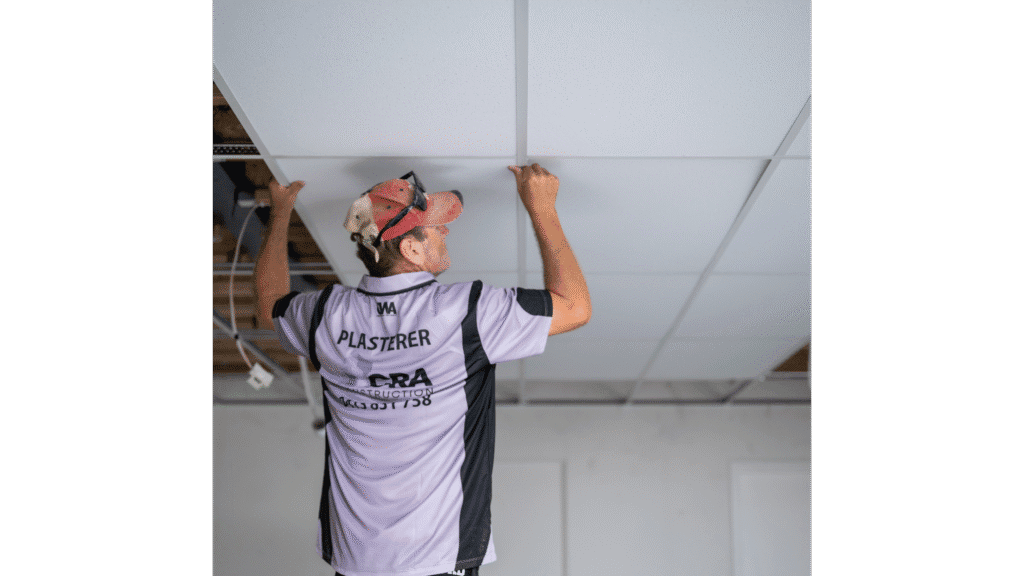 Skilled CRA Construction worker installing ceiling tiles in commercial space for quality interior finish.