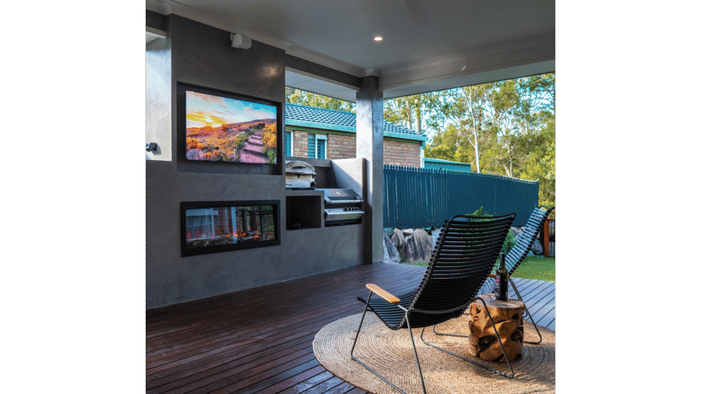 Outdoor living area with TV, fireplace, and seating by CRA Construction.